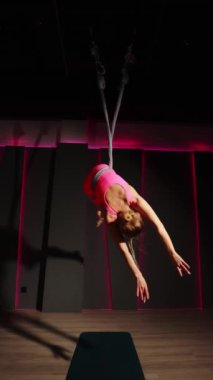 Spor salonunda güzel bir kız, egzersiz yapıyor, pembe bir arka planda geriniyor..