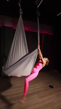 Genç bir kız hamakta hava yogası yapıyor.