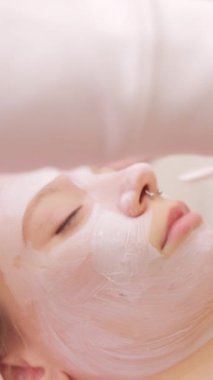 Güzellik salonunda yüzüne maske takan genç bir kadın..