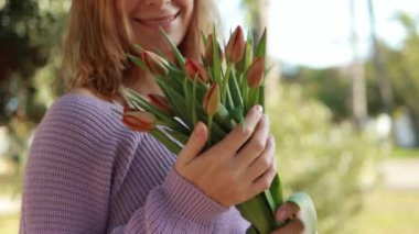 Elinde taze bir buket kırmızı lale tutan bir kadın..