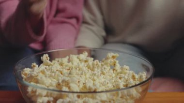 Çift patlamış mısır yiyor ve evde televizyon izliyor, erkek ve kadın patlamış mısır yiyor, yakın plan -