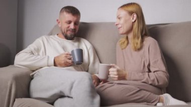 Bir çift genç adam ve kadın yatakta oturuyor.