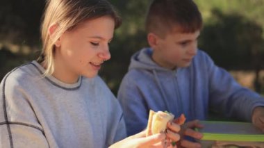 Oğlan ve kız ormanda kahvaltı yapıyorlar.