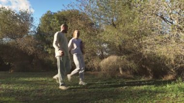 Beyaz elbiseli ve siyah şapkalı bir kadın. Sırt çantası çimlerin üzerinde.