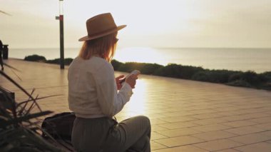 Plajda tabletli güneş gözlüklü kadın.