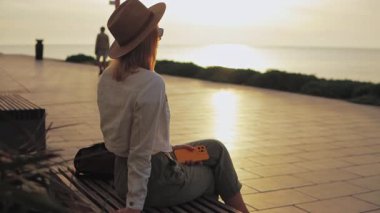 Sırt çantası ve tabletle bankta oturan kız..