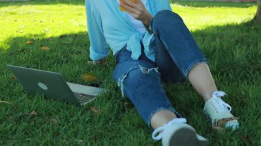 Parktaki dizüstü bilgisayarda çalışan günlük kıyafetli güzel bir kadın..