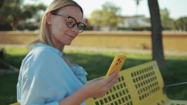 Parkta akıllı telefon kullanan bir kadın.