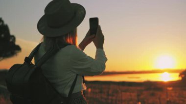 Akıllı telefonlu bir kadın gün batımında selfie çekiyor..
