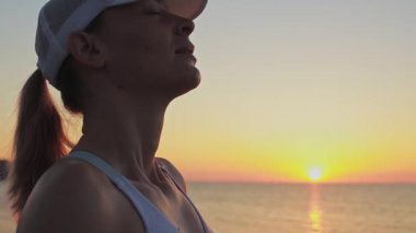 Uzun sarı saçlı güzel genç bir kadın, akşamları güneşin doğuşunun tadını çıkarıyor..