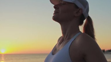 Gün batımında kumsalda güneşli bir kadın