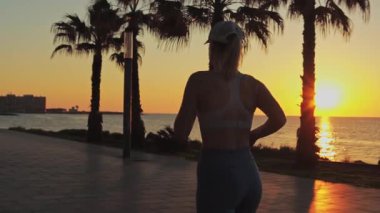 Kumsalda dizüstü bilgisayarı olan genç bir kadın. Gün batımı. Beyaz tişörtlü kız..