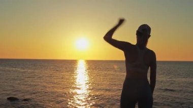Gün batımında sahilde genç bir adamın silueti.