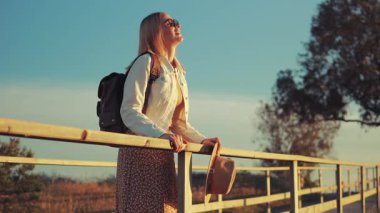 Sırt çantalı kadın gün batımında parkta.