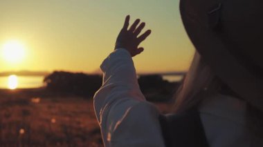 Gün batımının arka planında şapkalı bir kızın silueti..