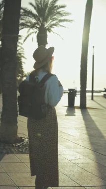 Kumsalda sırt çantalı şapkalı bir kız.