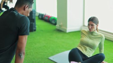 Genç çift spor salonunda antrenörleriyle egzersiz yapıyor.