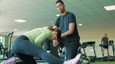 Kadın ve erkek spor salonunda kişisel antrenörle egzersiz yapıyor.