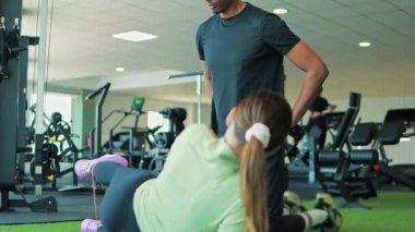 Kadın ve erkek spor salonunda halterlerle egzersiz yapıyor.