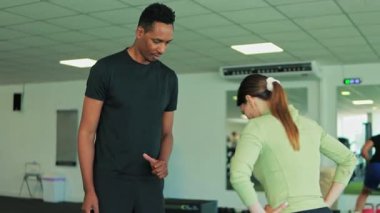 Genç adam spor salonunda koçla egzersiz yapıyor.