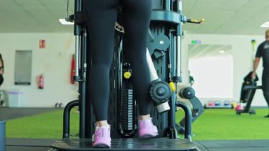 Spor makinesinde egzersiz yapan genç bir kadın.