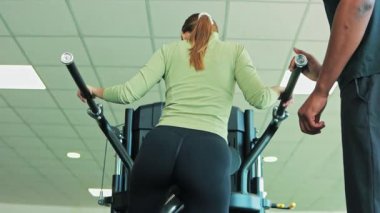 Spor salonunda bacaklarıyla egzersiz yapan genç bir kadın.