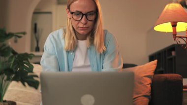 Evde dizüstü bilgisayar kullanan orta yaşlı serbest çalışan bir kadın.