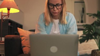 Genç ve güzel bir kadın gece odasında dizüstü bilgisayar kullanıyor.