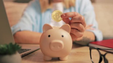 Kadın kumbaraya para koyuyor, para biriktiriyor.