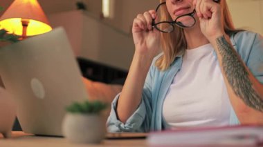 Evde dizüstü bilgisayar kullanan sıradan giysili genç bir kadın.