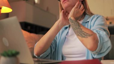 Gözlüklü genç kız dizüstü bilgisayar kullanıyor ve kameraya gülümsüyor..