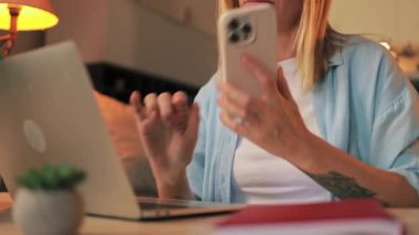 Genç kız mutfakta dizüstü bilgisayarla çalışıyor.