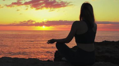 Günbatımında meditasyon yapan genç bir kadın.