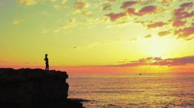 Gün batımında sahilde bir kadının silueti..