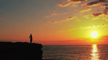 Denizde gün batımlı kadın silueti