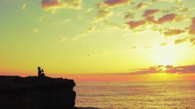 Kumsalda sırt çantalı bir adamın silueti.