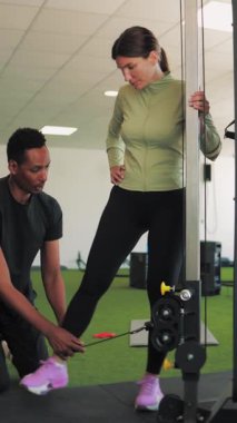 Kişisel koç spor salonundaki antrenörüyle kadına yardım ediyor.