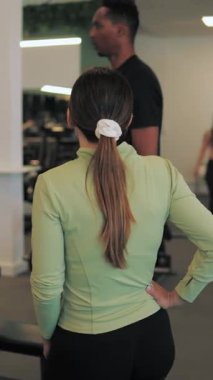 Antrenör, kadına egzersiz yapmayı öğretiyor.