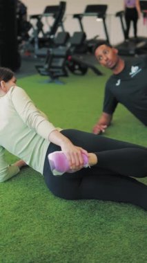 Spor salonunda şınav çeken genç bir kadın. Kişisel antrenör egzersiz yapıyor..