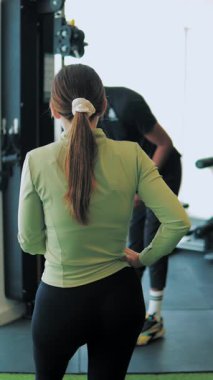 Spor salonunda esneme hareketleri yapan genç bir kadın. Spor salonunda spor yapan spor eğitmeni.