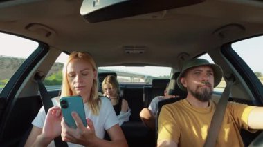 Kadın ve erkek arabada cep telefonu kullanıyor, aile gezisi.