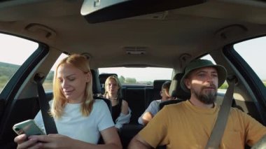 Arkadaşlar arabada akıllı telefon kullanıyor.