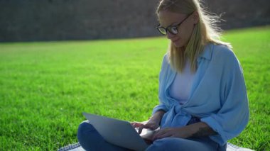 Parkta dizüstü bilgisayarı olan genç bir kadın.