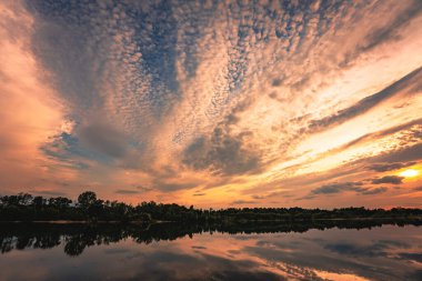 Gün batımından sonra bir orman gölünde dramatik bir alacakaranlık. Gölde yansıtılan güzel gün batımı.