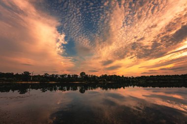 Gün batımından sonra bir orman gölünde dramatik bir alacakaranlık. Gölde yansıtılan güzel gün batımı.
