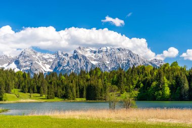 Geroldsee Gölü 'nde ahşap kulübeler ve Karwendel Dağı karla kaplı.