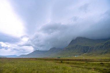 Doğu İzlanda 'da Reydarfjordur yakınlarında yüksek dağları ve dramatik bulutları olan gizemli bir manzara.