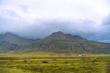 Doğu İzlanda 'da Reydarfjordur yakınlarında yüksek dağları ve dramatik bulutları olan gizemli bir manzara.