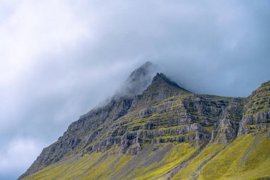 Doğu İzlanda 'da Reydarfjordur yakınlarında yüksek dağları ve dramatik bulutları olan gizemli bir manzara.