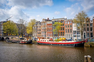 Amsterdam Kanalı üzerinde nefes kesici bir günbatımı. Tarihi Hollanda binalarından ve sakin sulardan yansıyan altın ışıkla.